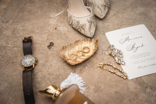 detail ring photo with a wristwatch shoes and invitation and brass leaf with rings inside