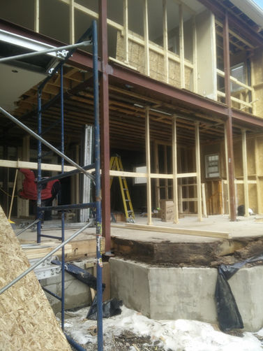 Rear addition construction showing exposed foundation, new wall framing, and temporary supports in Forest Hill.