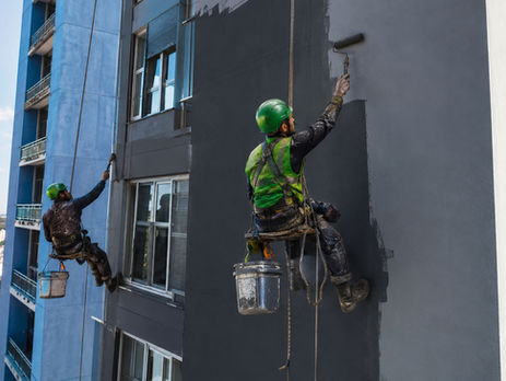 dois homens pintando um edifício na parte externa de rapel