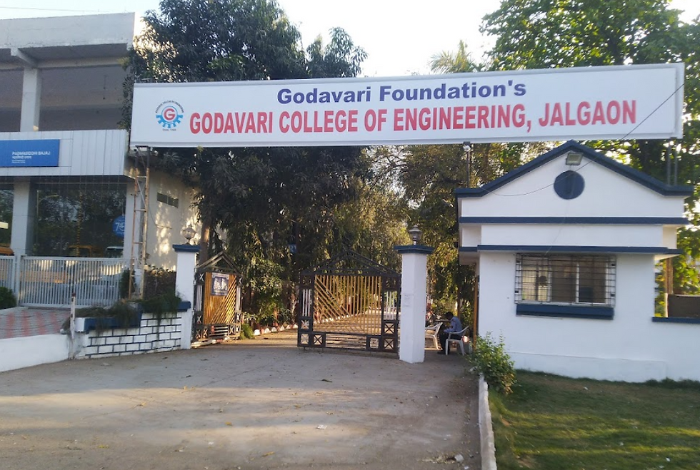 Entrance of Godavari College of Engineering, Jalgaon, with a white sign, trees in the background, and a metal gate. Sunny day.
