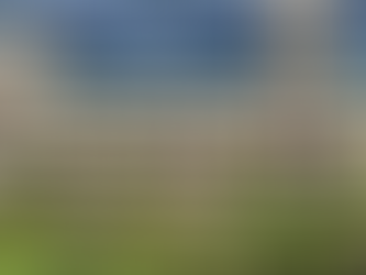 Large building with teal roof under stormy sky, surrounded by palm trees and greenery. People stand on balconies. Mood is tense and dramatic.