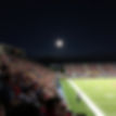friday night high school football game. lights are bright and bleachers are full. Crowd is