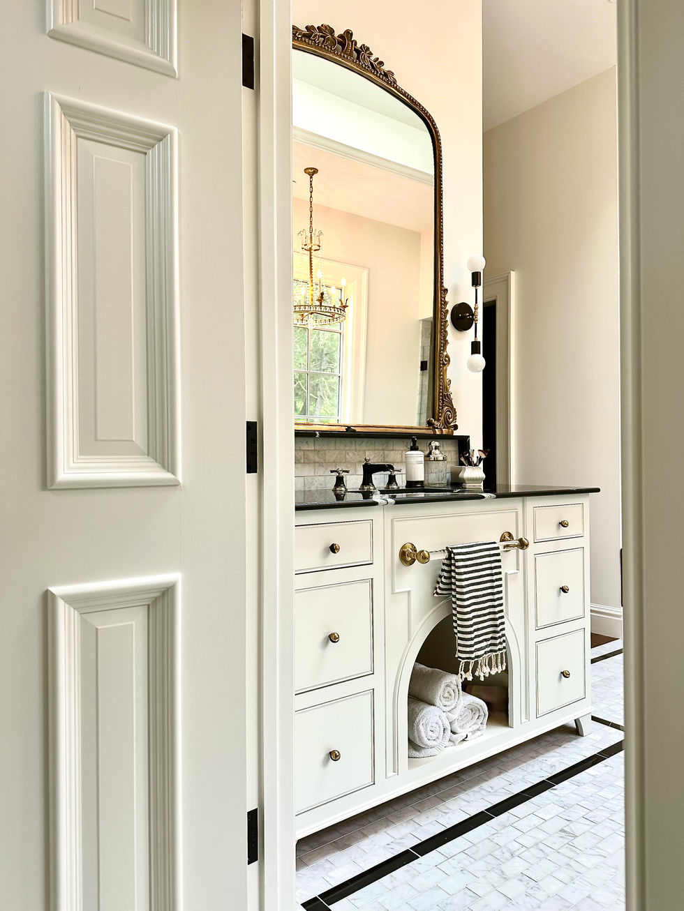 Custom white vanity with black marble counter top in elegant Colonial home.