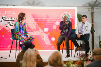 three men sit on a stage with a disco screen background at the 2025 Picnic in the Park event benefitting Madison Parks Foundation