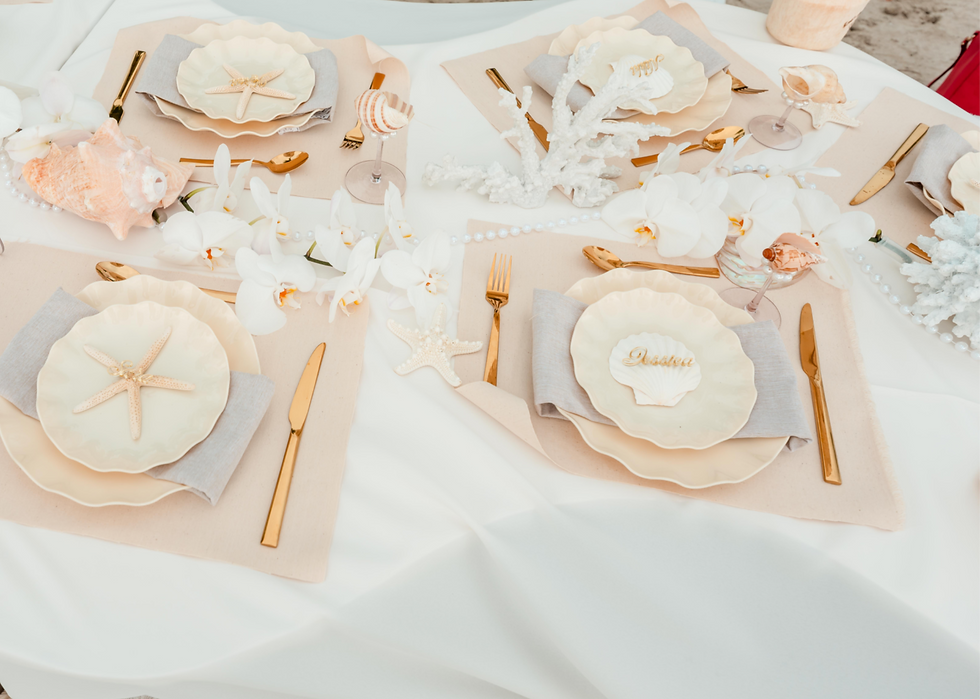 The seashell-inspired tablescape featured layered shell dinnerware, fresh orchids, coral accents, personalized place settings, gold flatware, and elegant coastal details designed exclusively for the bride and her guests.