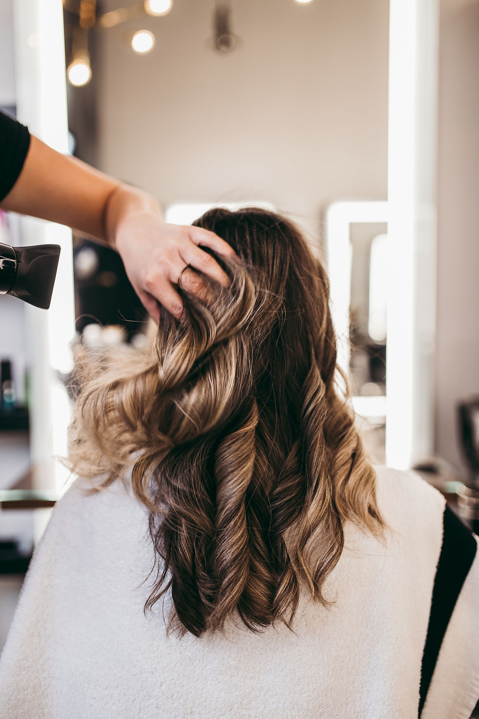 Stylist blow-drying curled brunette hair in a salon