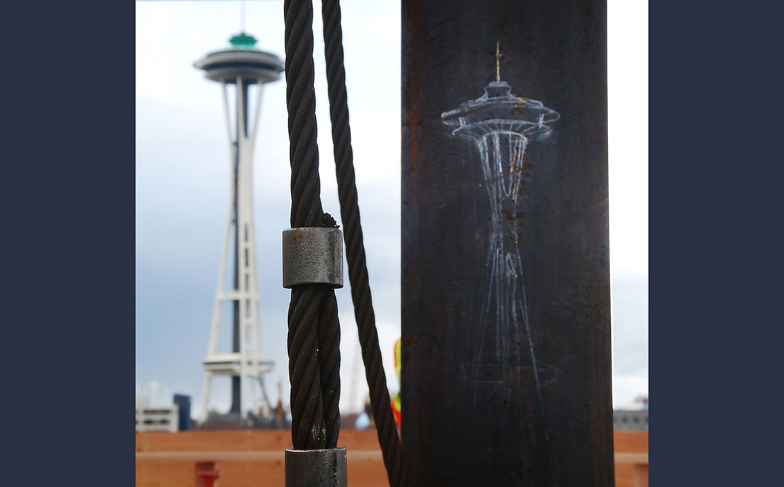 Photo of Seattle space needle with chalk drawing of space needle on steel column in front