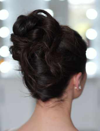 Modern French twist on long brown hair with loose bits 