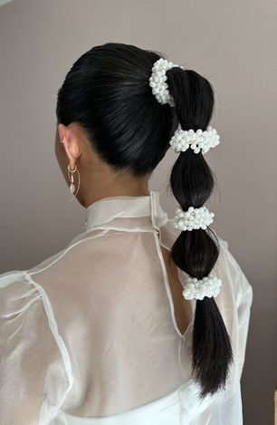 Alternative wedding ponytail on bride with black hair with pearl accessories. 