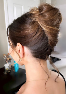 Modern French twist with loose bits on bride with dark hair with blonde highlights 