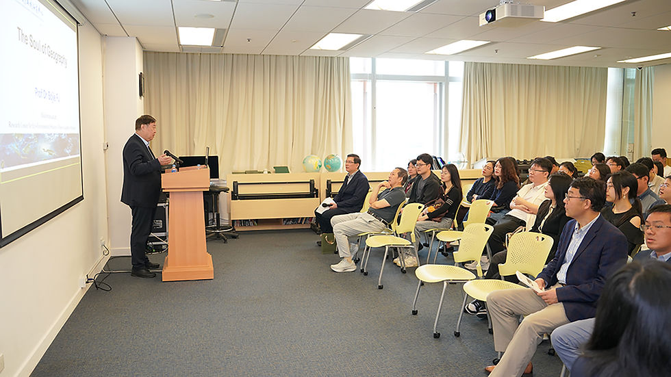 Professor speaks at a podium as students watch a projected slide reading The Soul of Geography in a bright classroom.