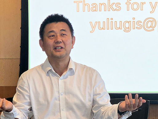 Man in white shirt speaks with open hands before a projector slide reading Thanks for your yuliugis@pku…