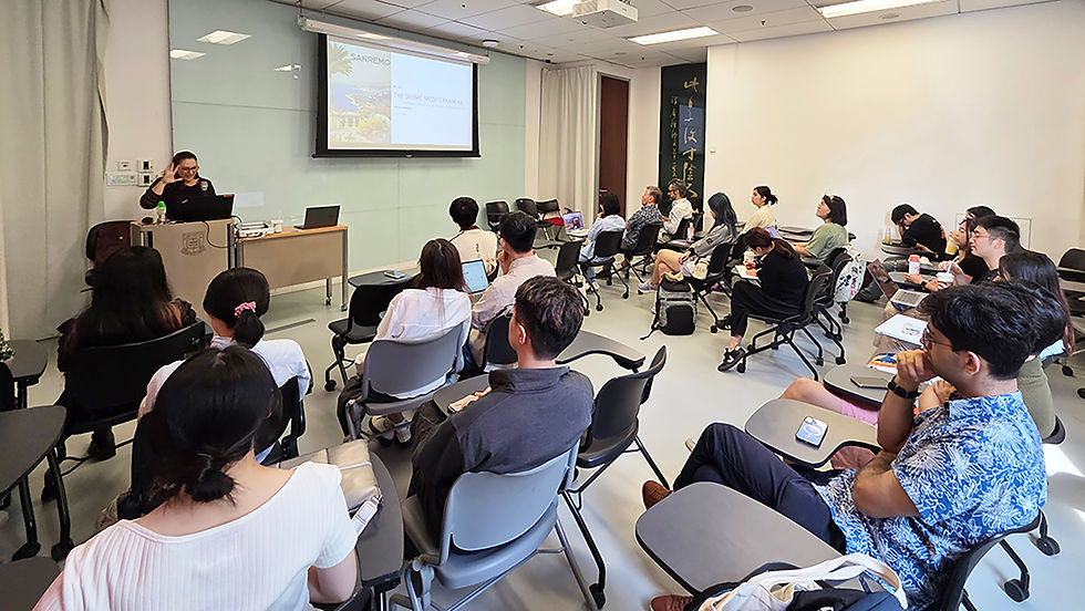 Presenter speaks at a podium during a classroom lecture, with seated audience and a slide reading SANREMO and The Scenic Mediterranean.