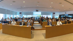 Audience in a bright lecture hall listens to a presentation titled Managing Regional Innovation and Inequality in the AI Age.