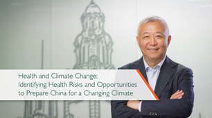 Smiling man in suit beside title slide reading Health and Climate Change: Identifying Health Risks and Opportunities, with tower backdrop.