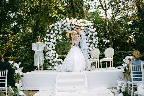 Couple de mariés s’embrassant sous une arche fleurie, cérémonie de mariage à Montpellier Occitanie
