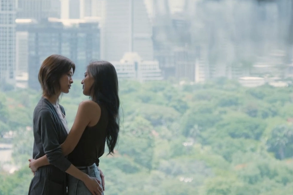 Chan and Key embrace in Chan’s apartment in Moonshadow Episode 2, standing before a large window overlooking a Bangkok park.