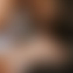 Two women in bed, leaning in for an intimate kiss, full of tenderness.