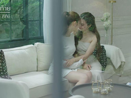 Seen through a window, Lin and Jane sit close on a couch with their foreheads touching in an intimate moment after Lin chooses to stay in Thailand with Jane.