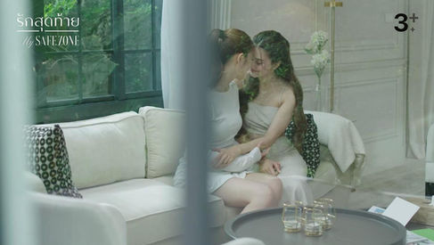 Seen through a window, Lin and Jane sit close on a couch with their foreheads touching in an intimate moment after Lin chooses to stay in Thailand with Jane.