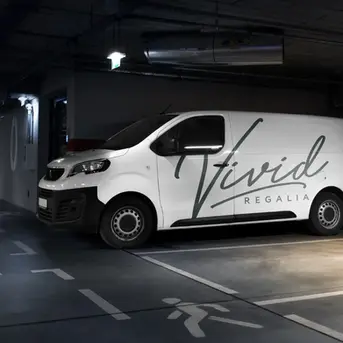 Branded delivery van for Vivid Regalia featuring elegant handwritten typography and a clean design for impactful vehicle marketing, parked in an underground parking garage