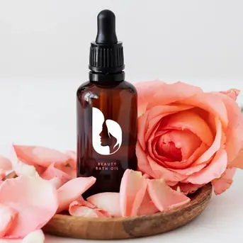 Elegant product packaging design for Beauty Bath Oil, featuring a feminine silhouette logo on an amber glass bottle surrounded by rose petals.