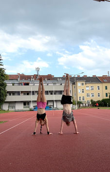 Zwei Personen machen Handstand auf einem Sportplatz