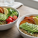 Two vibrant, plant‑based bowls filled with avocado, lentils, roasted sweet potatoes, cucumbers, cherry tomatoes, lemon wedges