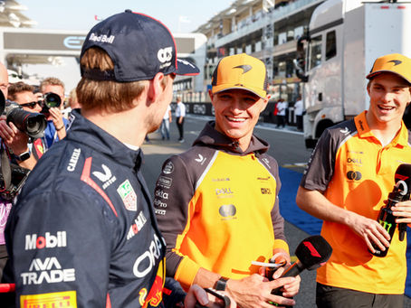 Max Verstappen looking at Lando Norris and Oscar Piastri during an interview on an F1 track