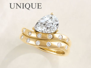 Pear shaped diamond on gold band with smaller diamonds across