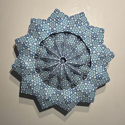 Top view of Lunar Lotus Bloom in its open circular orientation, formed from folded geometric paper modules.