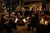 Strykeensemble spiller under aperitiff på et eksklusivt julebord med juledekor, levende lys og minglende gjester.