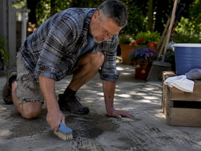 Homeowner scrubbing oil stain on driveway