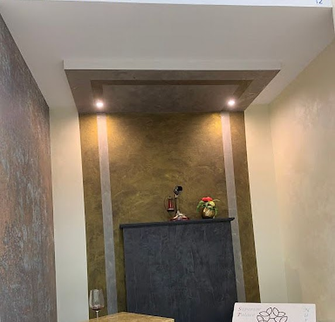 Edle Wand- und Deckenverkleidung mit metallic-goldenem Strukturputz, indirekter Beleuchtung und Kaminverkleidung – hochwertig