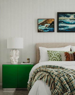 A mid-century inspired bedroom with textured walls that has a wavy white table lamp on a green nightstand