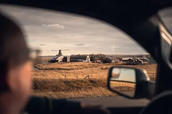 Weerspiegeling van open landschap in zijspiegel tijdens autorit
