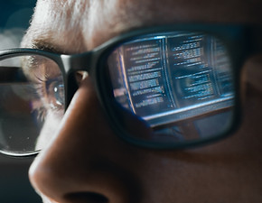 Man with glasses with reflection of computer screen on glass