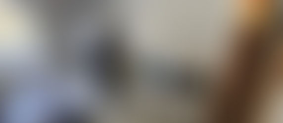 Servidora da Polícia Civil do DF de costas, sem identificar, enquanto investiga materiais sob uma cama, em um quarto que aparenta ser um escritório