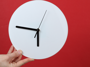 a hand holding a white clock