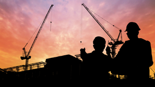 Construction workers and cranes at sunset