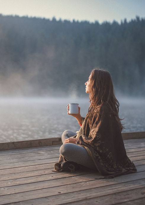 Femme tranquille, qui boit son thé devant un lac