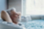 Elderly man relaxing in a whirlpool bathtub, demonstrating the therapeutic benefits and comfort advantages over standard bathtubs.