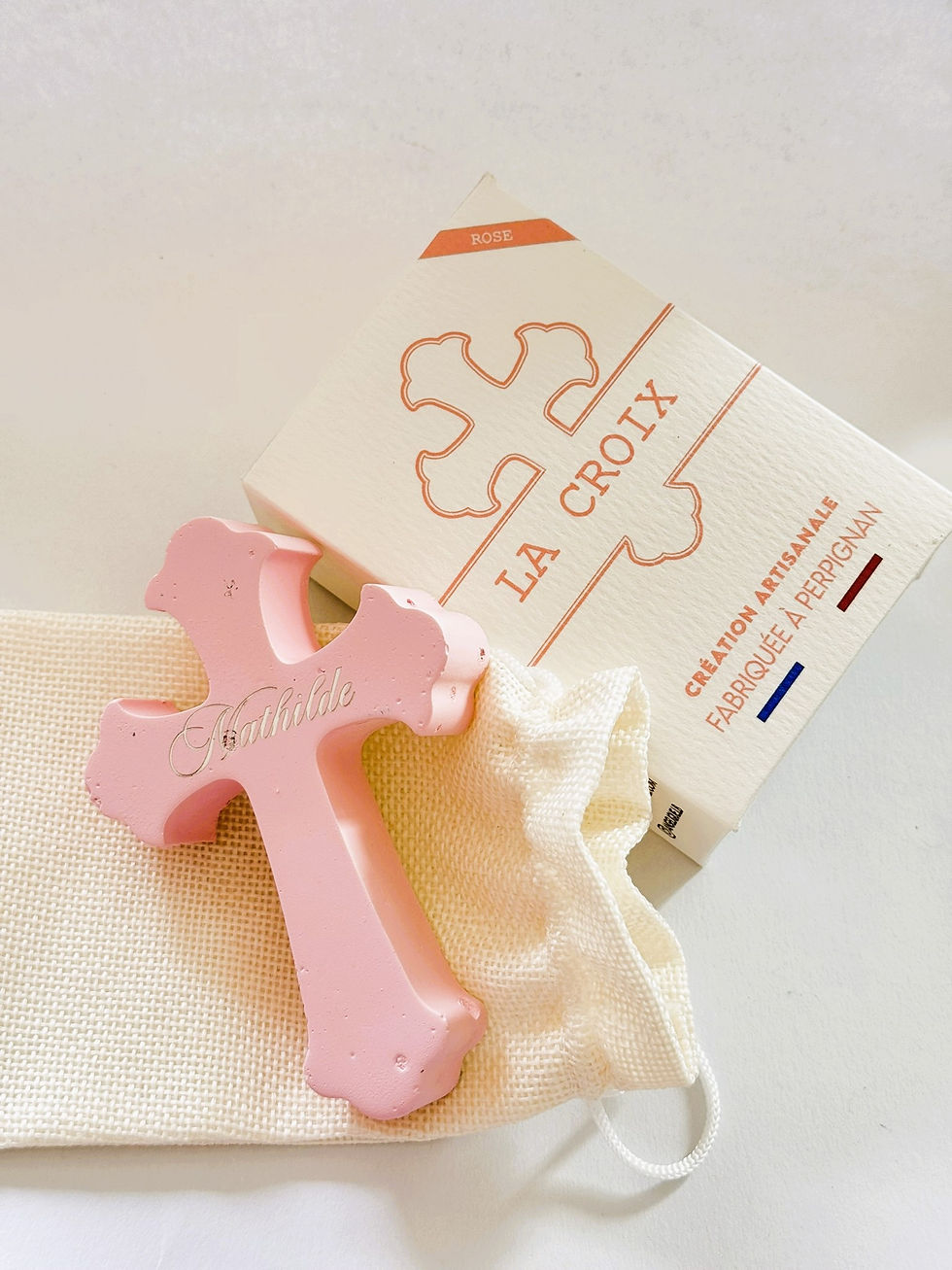 Croix florencée rose gravée avec un prénom, fabrication artisanale à Perpignan.