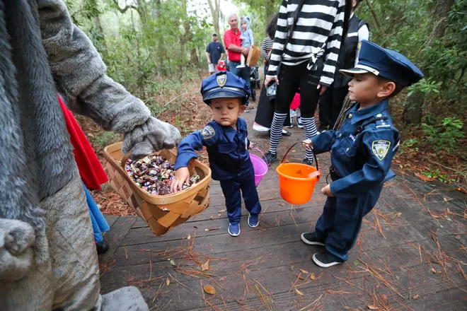 Ryker and Dakota Bouknight pick up treats at one of the stops along the trail during the annual Oatland Island Halloween Hike on Friday, October 13, 2023. Richard Burkhart/Savannah Morning News