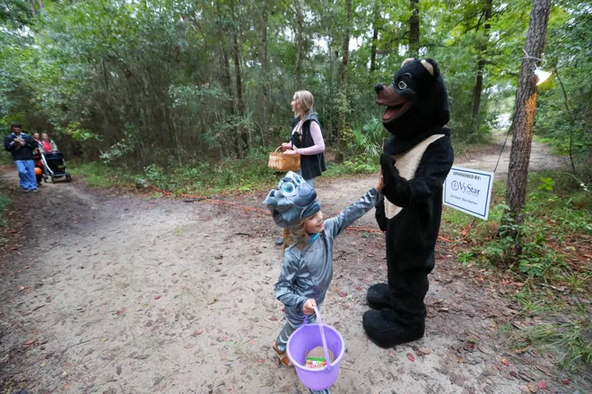 A young trick or treater gives a bear a high five during the annual Oatland Island Halloween Hike on Friday, October 13, 2023. Richard Burkhart/Savannah Morning News