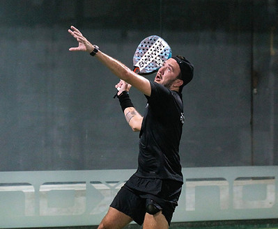 Padel player catching the ball mid-air