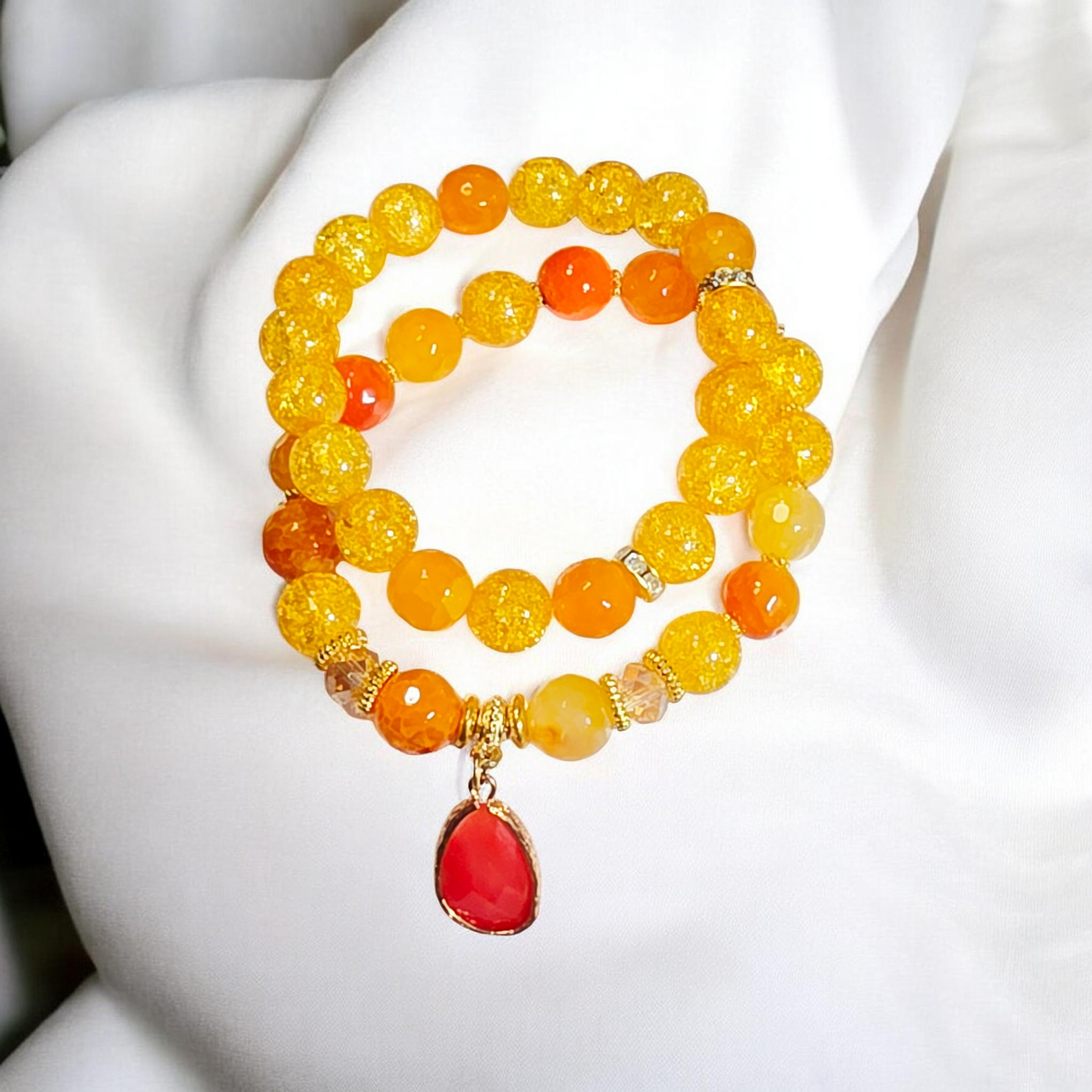 Stackable beaded bracelet duo with yellow beads and red charm.