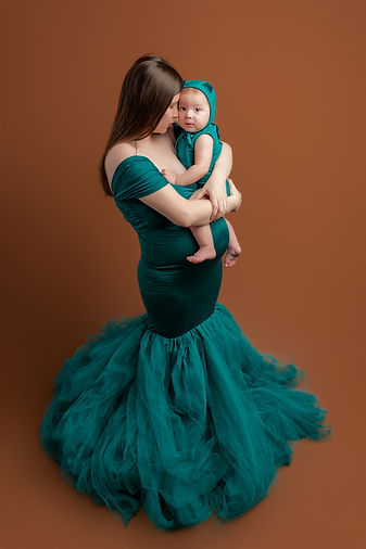 Brother rests on mom's pregnant belly while they wear color coordinated outfits.
