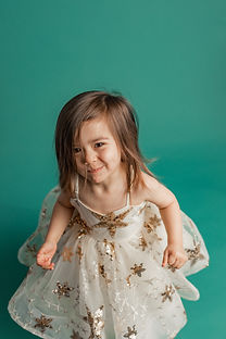 Toddler girl wearing sparkly dress smirking for the camera.