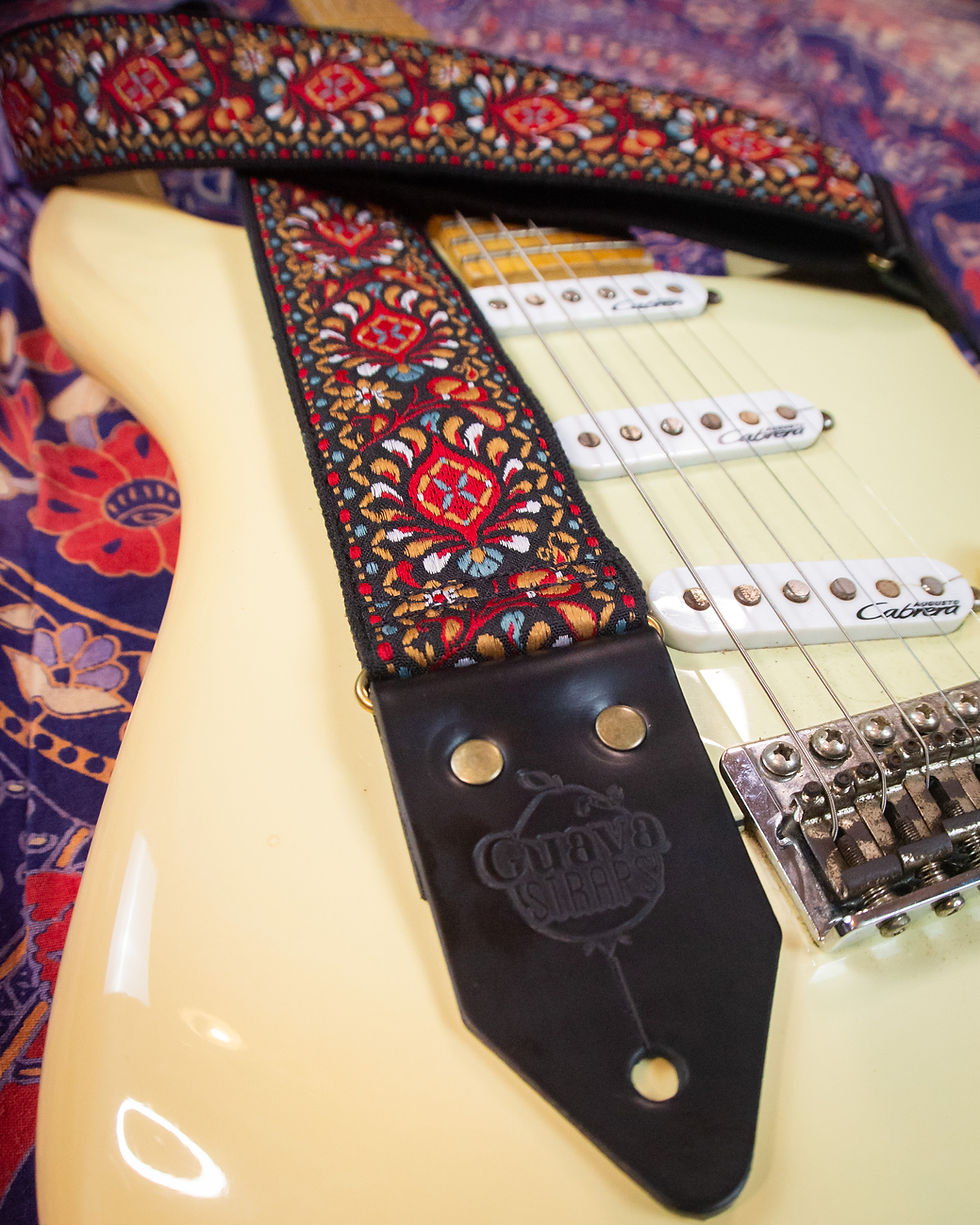 Miniatura: Correia Opium vermelha tem padrão floral vermelho e está sobre guitarra creme